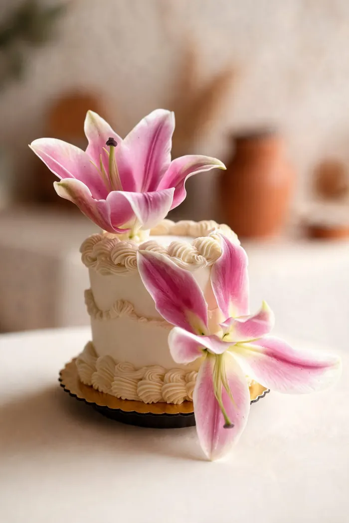 Torta pequeña decorada con lirios rosados naturales