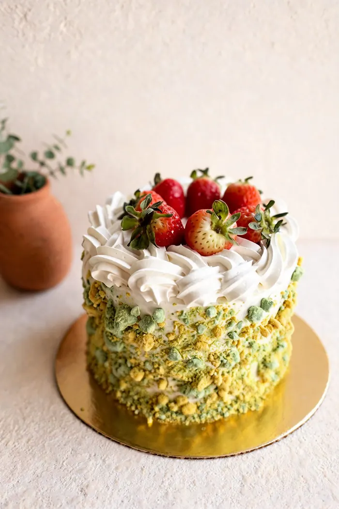 Torta con fresas frescas encima y borde de pistacho