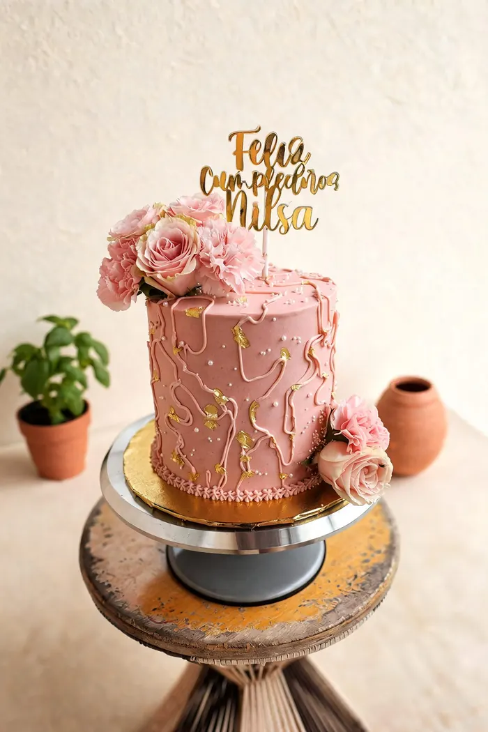 Torta rosa decorada con hojuelas de oro comestible y flores